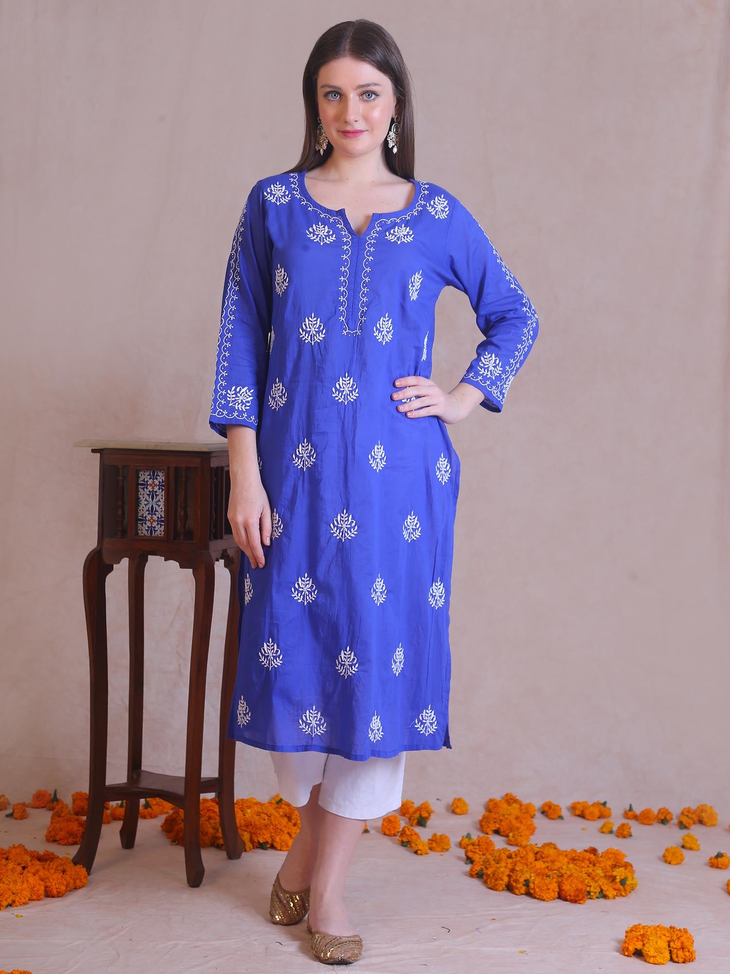 Woman wearing a blue kurta with white patterns on a beige background